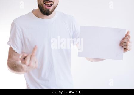 Bearded man holding a blank white sheet of paper. Angry young guy showing fingers at camera. Stock Photo