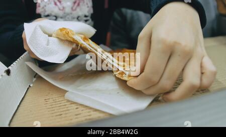 Mother and daughter eat pizza cheese four. Close up of young woman eating pizza and chewing in outdoor restaurant. Girl hands taking pieces pizza. Stock Photo