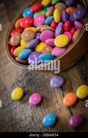 Colorful candies in a wooden bowl case isolated on wood background Stock Photo
