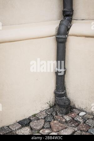 Vertical shot of a pipe going in front of a wall into the ground Stock Photo