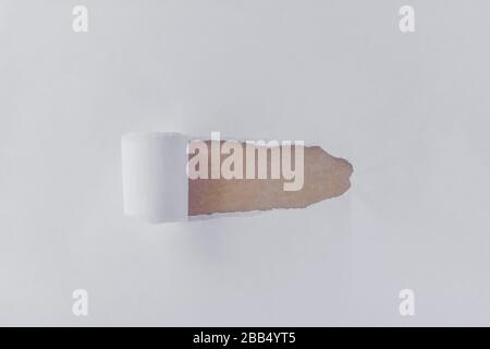 Torn white paper with opening showing brown background Stock Photo