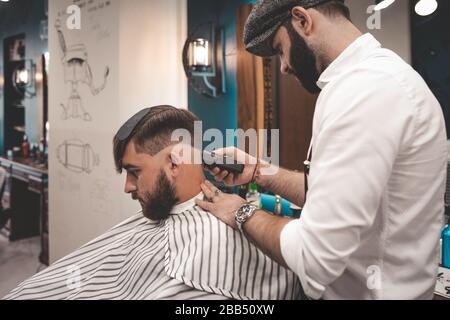 serious bearded guy doing haircut in barbershop. barbershop concept Stock Photo