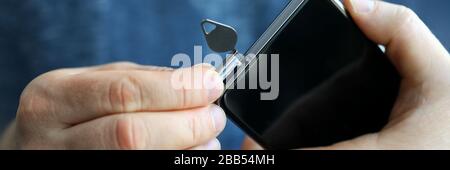 Male hands getting sim card slot of his smartphone out Stock Photo