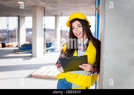 Female construction worker with a clipboard in hand inspects the construction process Stock Photo