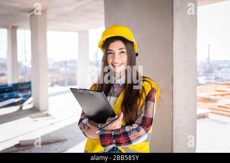 Female construction worker with a clipboard in hand inspects the construction process Stock Photo