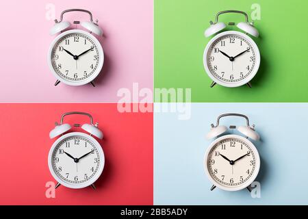 White vintage alarm clock on blue, pink, red and green backgrounds. Time concept Stock Photo