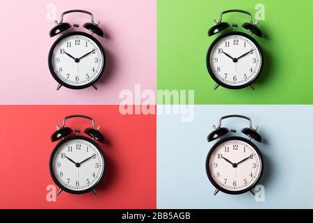 Black vintage alarm clock on green, pink, red and blue backgrounds. Time concept Stock Photo