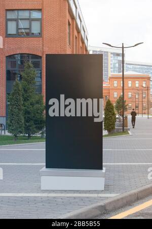 Blank black vertical pylon stand mockup brick building background Stock Photo