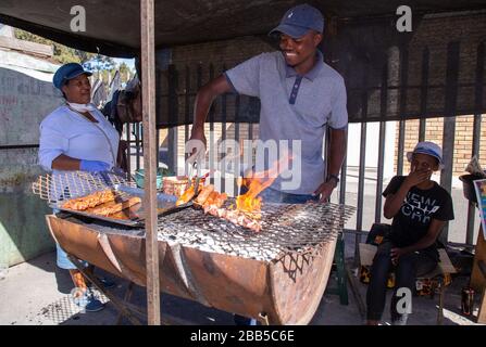 Cape Town, South Africa. 30th Mar, 2020. people making a braai (BBQ) outside a shopping centre in Philippi as shoppers and social grant payees wait in line to collect their money after the South African government declared a 21 day COVID-19 lockdown as part of the State of National Disaster declaration by President Cyril Ramaphosa. The Health Ministry has asked residents to observe the regulations, practise hygiene, stay at home and practise social distancing. Credit: Roger Sedres/Alamy Live News Stock Photo