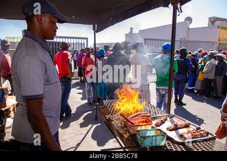 Cape Town, South Africa. 30th Mar, 2020. people making a braai (BBQ) outside a shopping centre in Philippi as shoppers and social grant payees wait in line to collect their money after the South African government declared a 21 day COVID-19 lockdown as part of the State of National Disaster declaration by President Cyril Ramaphosa. The Health Ministry has asked residents to observe the regulations, practise hygiene, stay at home and practise social distancing. Credit: Roger Sedres/Alamy Live News Stock Photo