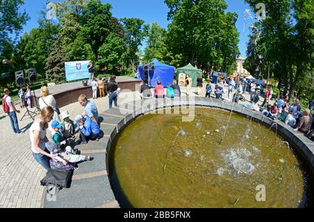 Smiling people enjoying spring sunny day playing with children near fountain at the park. Mother Day. May 12, 2019. Kiev, Ukraine Stock Photo
