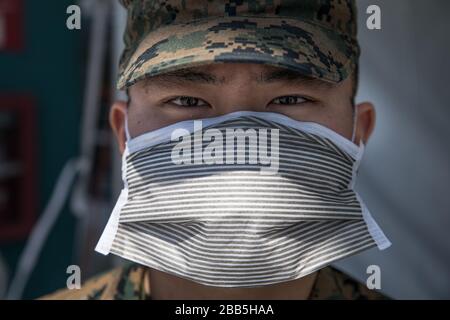 Los Angeles, United States of America. 29 March, 2020. U.S. U.S. Marine Pfc. Brandon Shim, wearing personal protective equipment, guards the checkpoint for the Military Sealift Command hospital ship USNS Mercy as it begins treating patients in support of the COVID-19 pandemic March 29, 2020 in Los Angeles, California. Credit: Alexa Hernandez/U.S. Navy Photo/Alamy Live News Stock Photo