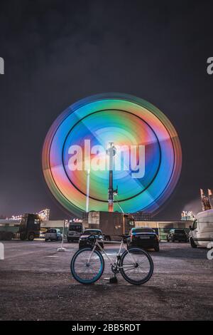 A fair ride shot with a long exposure at night with a bike in the center, Munich, Germany Stock Photo