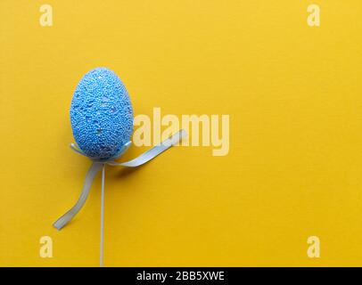 Easter minimalistic banner with copy space. Flat lay with copy space. Single blue egg yellow background. Stock Photo
