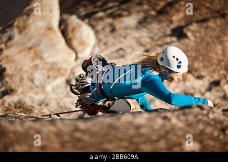 Mid-adult rock climber climbing on rocky part of mountain. Stock Photo