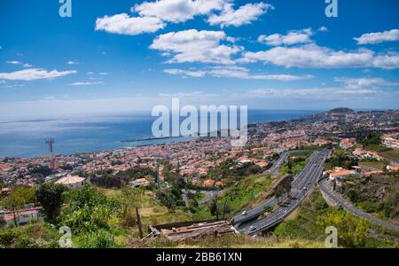 A view of Funchal on the island of Madeira taken from a viewpoint on a road to Monte on a sunny day with a blue sky and white clouds. Stock Photo