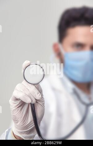 Close-up photo of male doctor in a protective mask using stethoscope . Isolated on white. Healthcare concept. epidemic corona virus outbreak concept Stock Photo