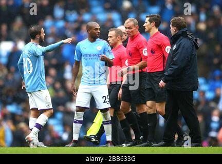 Manchester City's Bernardo Silva (left) and Fernandinho (centre left) exchange words with match referee Graham Scott Stock Photo