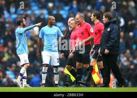 Manchester City's Bernardo Silva (left) and Fernandinho (centre left) exchange words with match referee Graham Scott Stock Photo