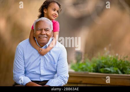 Little girl hugging her smiling grandfather. Stock Photo