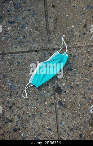 An abandoned surgical mask on a sidewalk in NYC. Stock Photo