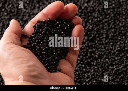 Granular recycled black plastic in hand Stock Photo