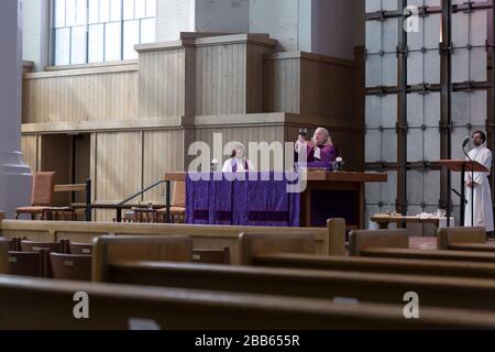 The Reverend Jennifer King Daugherty (c) gives the sacrament with the Reverend Nancy Ross (l) and altar guild Morgan Randall during a livestream-only service of Holy Eucharist at St. Mark's Episcopal Cathedral in Seattle on Sunday, March 29, 2020. In accordance with public health guidance, the cathedral closed to the public to prevent the spread of the COVID-19 virus. As a community service, the cathedral is broadcasting service via livestream in order to engage the community in worship and prayer. Stock Photo