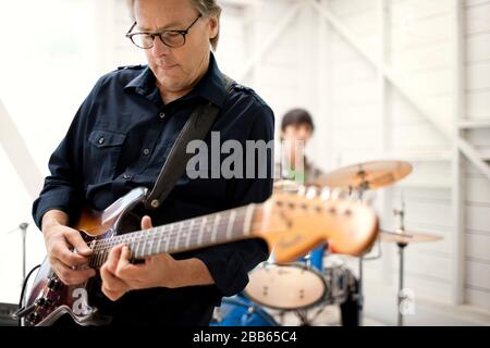 Mid adult man playing an electric guitar enthusiastically. Stock Photo