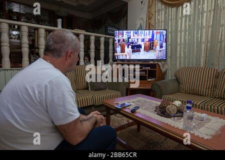 (200330) -- BETHLEHEM, March 30, 2020 (Xinhua) -- A Palestinian watches a live TV broadcast of Sunday Mass from an Orthodox church in Beit Sahour near the West Bank city of Bethlehem on March 29, 2020. For the first time ever, Raed al-Atrash, a 54-year-old Palestinian man from the West Bank city of Bethlehem, attended the Sunday Mass with his family through a live TV broadcast, as the churches are closed as part of the precautions against the spread of the novel coronavirus.TO GO WITH 'Feature: Christians in Palestine attend live prayers as churches close over coronavirus fears' (Photo by Luay Stock Photo