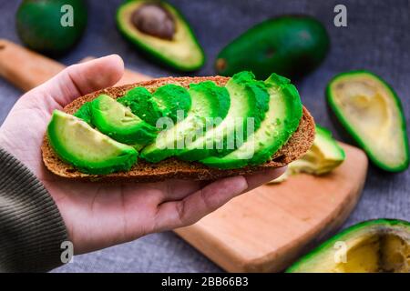 Healthy breakfast. Female hand holding Avocado toast Stock Photo