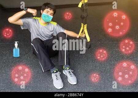 Young asian strong man in sportswear doing work-out, sports exercise training and wearing mouth mask against the corona virus in home fitness. Stock Photo