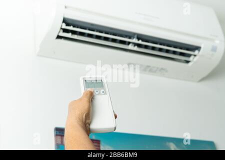 Remote control directed on air conditioner systrem, senior hand control air conditioner at home Stock Photo