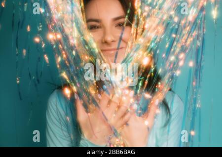 Portrait of a beautiful woman looking through a tinsel curtain