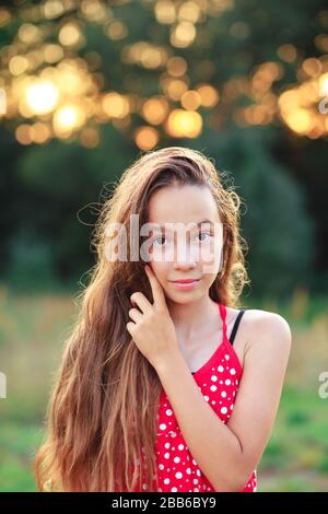 Beautiful Teen Girl is smiling and  enjoying nature in the park at Summer sunset Stock Photo