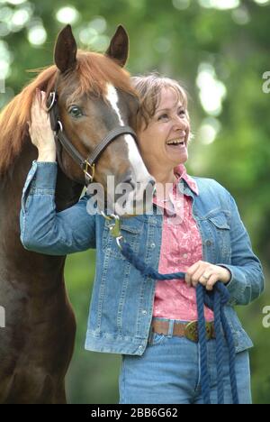 Mature woman standing with Arabian Horse colt Stock Photo