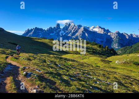 Man hiking in Dolomites with two friends in the distance, South Tyrol, Italy Stock Photo