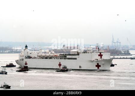 With an escort of police and fire boats and tugboats, the US Navy hospital ship, Comfort, arrived in New York Harbor around 10 a.m. on March 30. Stock Photo