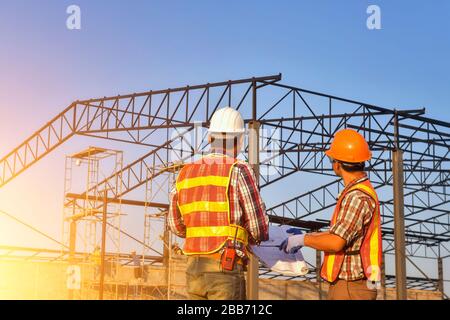 Two Construction workers on a construction site looking at plans, Thailand Stock Photo