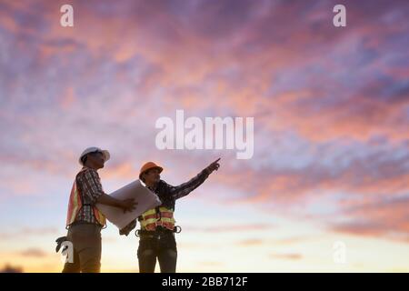 Two Construction workers on a construction site looking at plans, Thailand Stock Photo