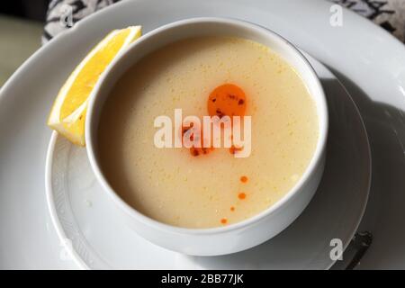 Turkish traditional lentil mashed soup (Turk Mercimek Çorbasi) on white ceramic bowl and slice of lemon on plate. Close up view. Stock Photo