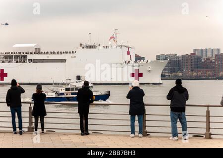 Visitors to Hudson River Park in New York greet the USNS Comfort hospital ship as it arrives in New York on Monday, March 30, 2020. The ship will berth at Pier 90 and use its 1,000 hospital beds to serve non-COVID-19 patients taken some of the burden off of New York hospitals. (© Richard B. Levine) Stock Photo