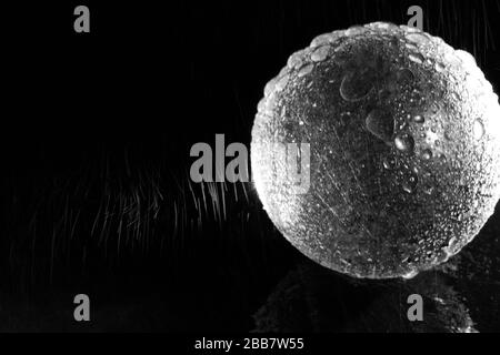 Bright Crystal Ball in the Rain on a Black Background, Black and White Photo Stock Photo