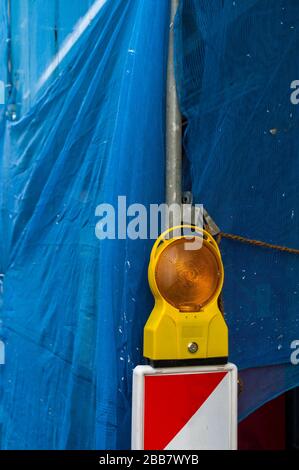 Warning light on bake in front of a construction site. House renovation. Renovation suspended with blue fabric Stock Photo