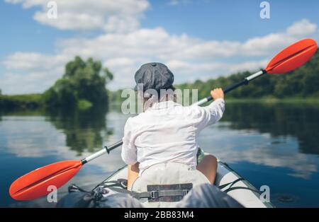 Young woman kayaking alone on a river without safety vest. Travel alone. Vacation period outside. Beautiful nature and sunny day Stock Photo