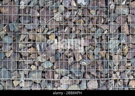 Gabion rock wall, stones in steel wire cage, decoration rocks cube in garden Stock Photo