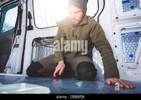 Man working inside his DIY camper van Stock Photo