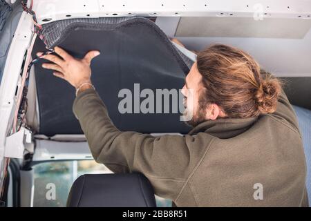 Man insulating the inside of his camper van Stock Photo