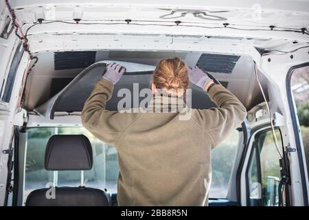 Man working on insulation inside his camper van Stock Photo