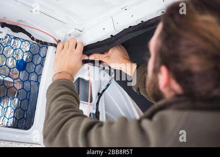 Man working on insulation inside his camper van Stock Photo