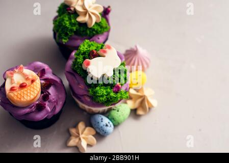 Easter cupcakes with different decorations made of chocolate and cream on a gray background. Stock Photo